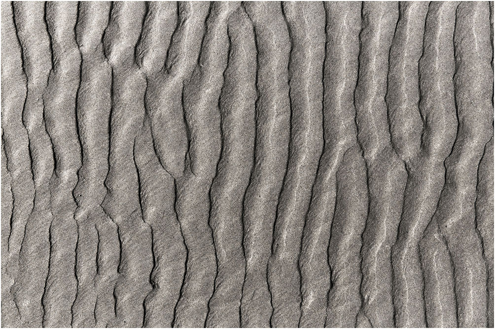 Geribbelde patronen in het zand langs de kustlijn